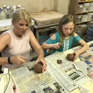 Adults and children crafting with clay together.