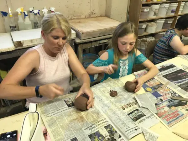 Adults and children crafting with clay together.